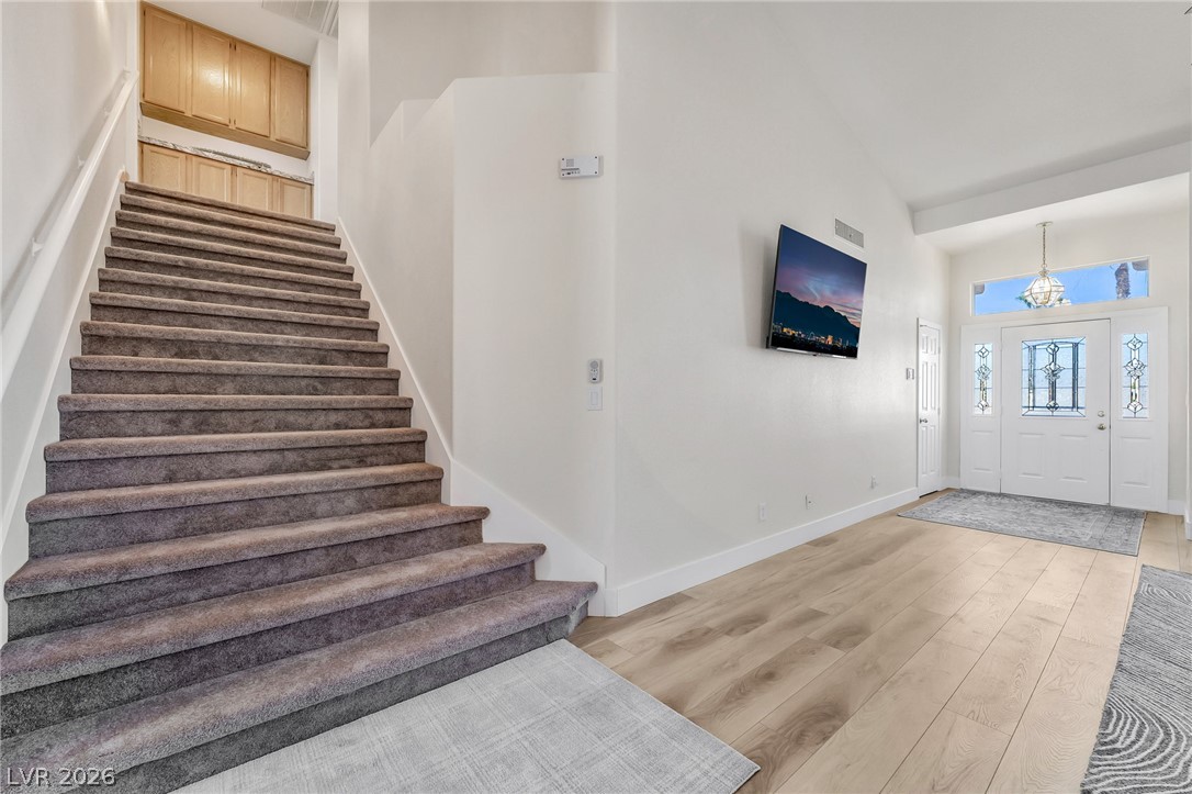 104 Appian Way Henderson, NV 89002 - Photo 4 of 24 A spacious entry showcases rich hardwood floors leading to a grand staircase and a decorative glass front door.