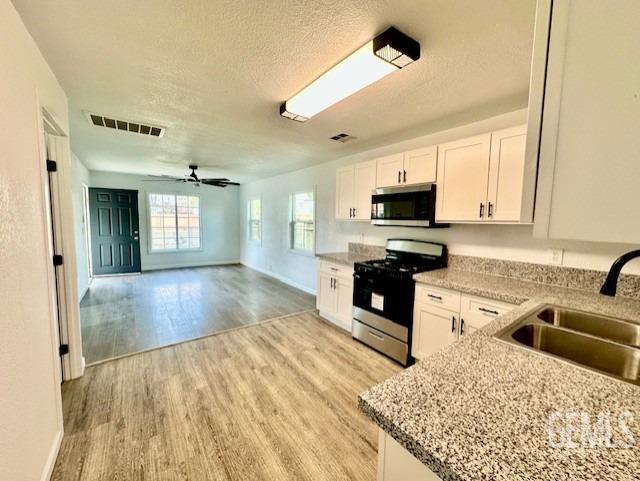Undisclosed Address Bakersfield, CA 93308 - Photo 6 of 16 a kitchen with stainless steel appliances granite countertop a stove top oven a sink dishwasher a dining table and chairs with wooden floor