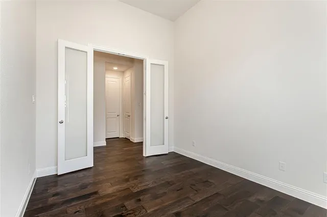 a view of an empty room with wooden floor and closet