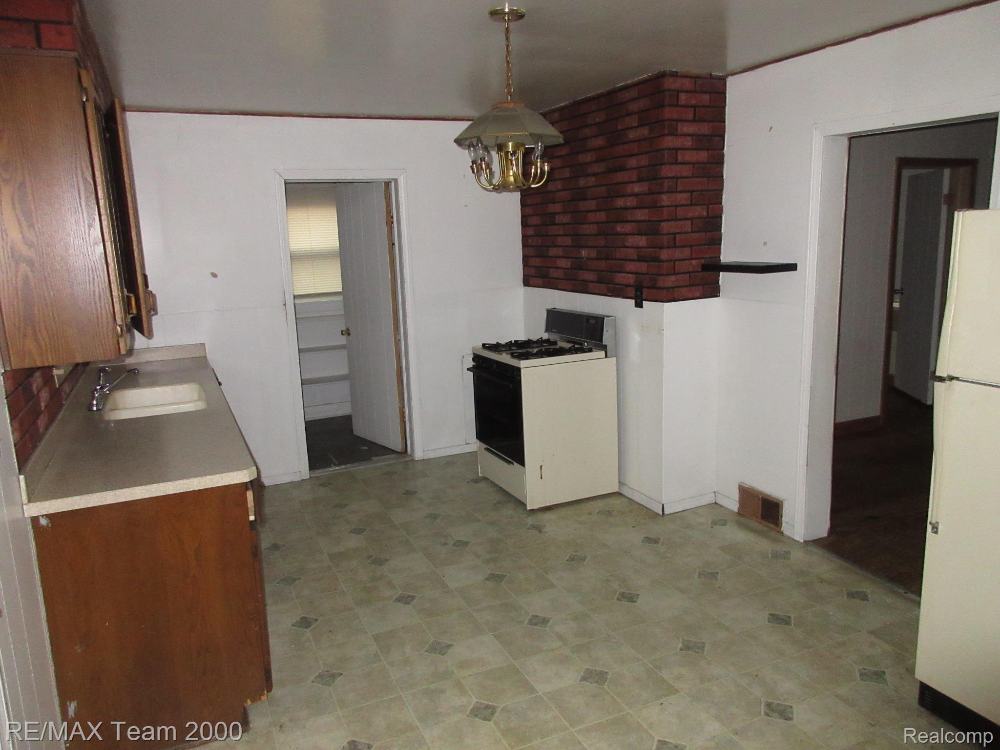 604 Smith Street Monroe, MI 48161 - Photo 16 of 24 Kitchen featuring a range with an overhead brick-patterned architectural element, base and upper cabinetry, a single basin sink, and patterned flooring