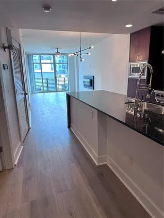 a large kitchen with stainless steel appliances a large counter top a wooden floor and a large window