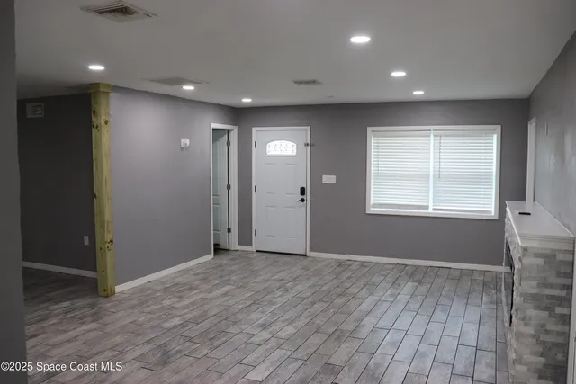 an empty room with wooden floor and windows