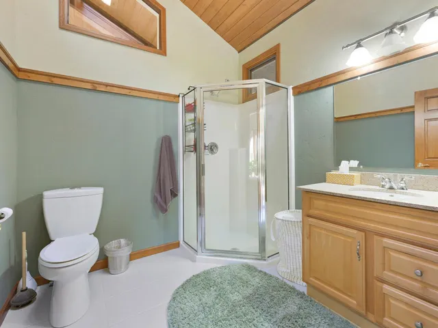 a bed sitting in a spacious bedroom next to a window and a chandelier