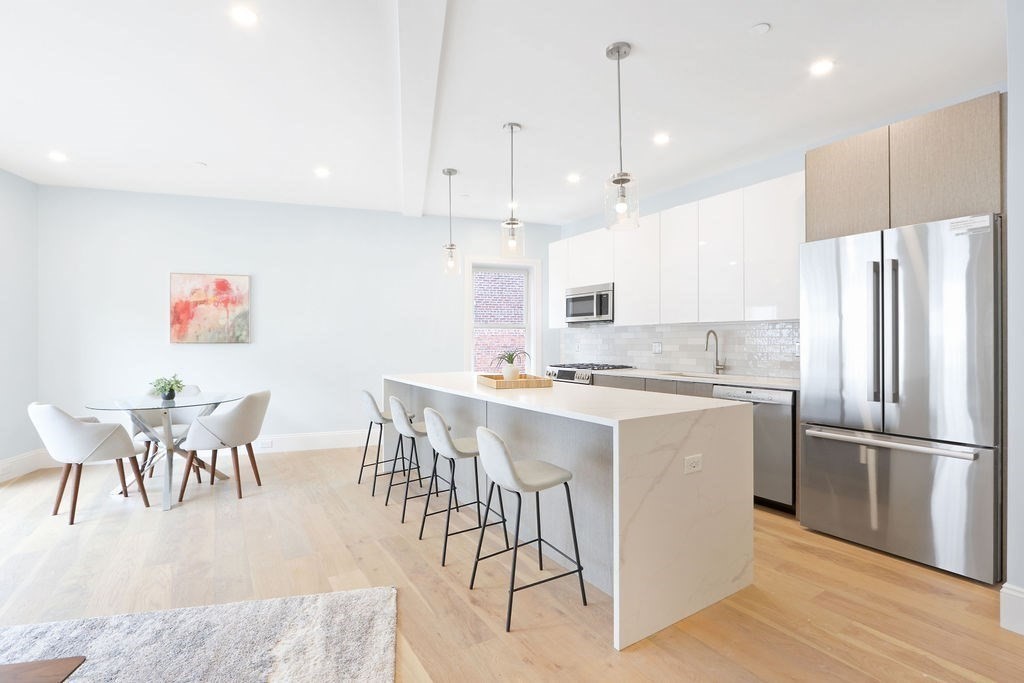 21 Glen Road, Unit 7 Boston, MA 02130 - Photo 2 of 15 a kitchen with stainless steel appliances granite countertop a refrigerator a sink a stove a dining table and chairs