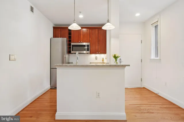 a kitchen with kitchen island granite countertop a sink cabinets and wooden floor