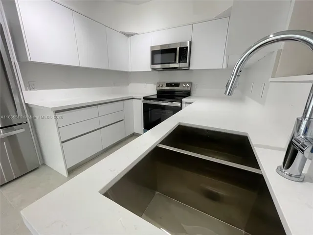 a kitchen with white cabinets and black appliances