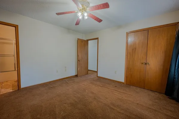 an empty room with closet and a chandelier fan