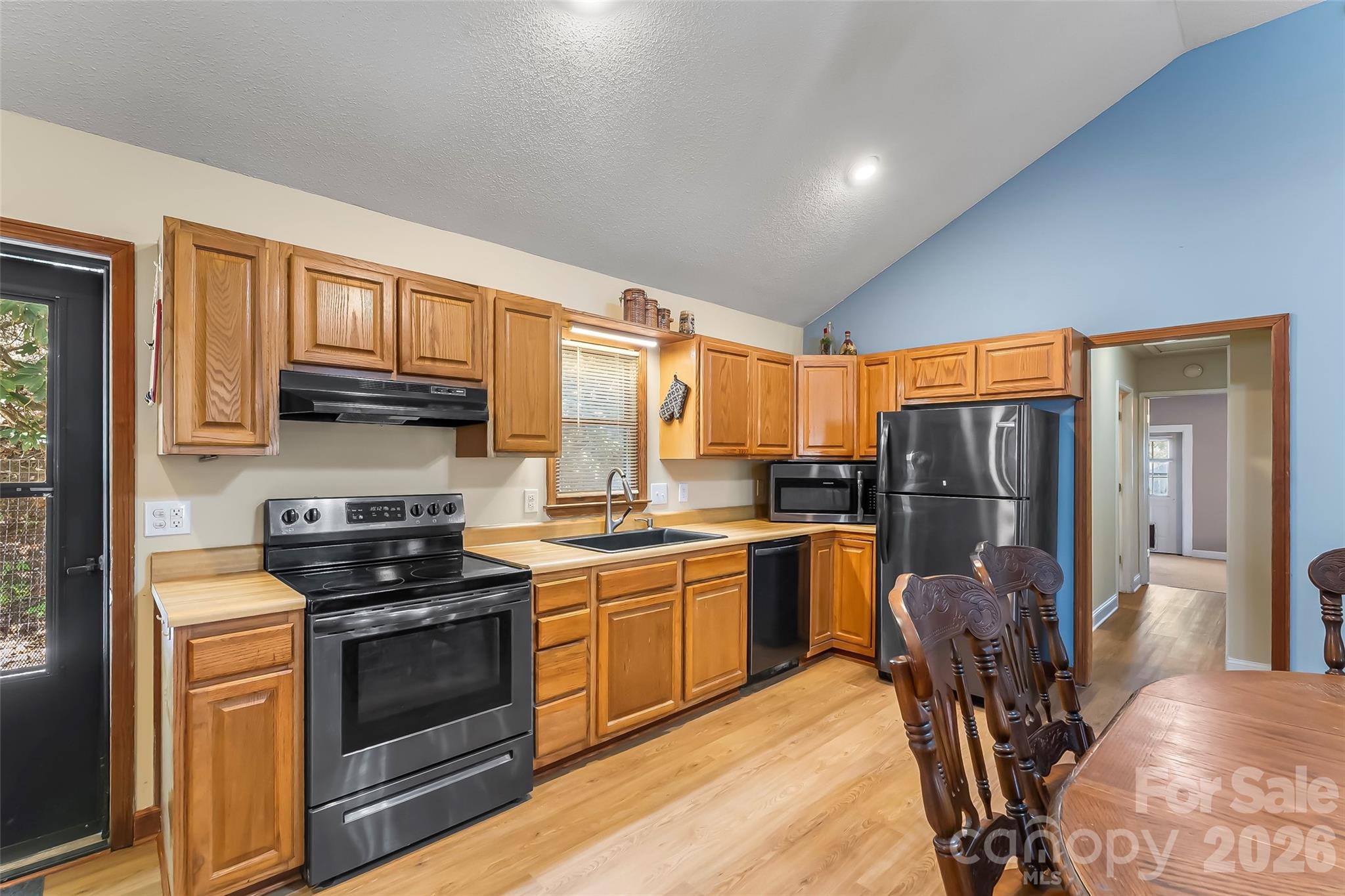 242 Plott Balsam Road Maggie Valley, NC 28751 - Photo 11 of 32 a kitchen with stainless steel appliances granite countertop a stove top oven a sink dishwasher a dining table and chairs with wooden floor