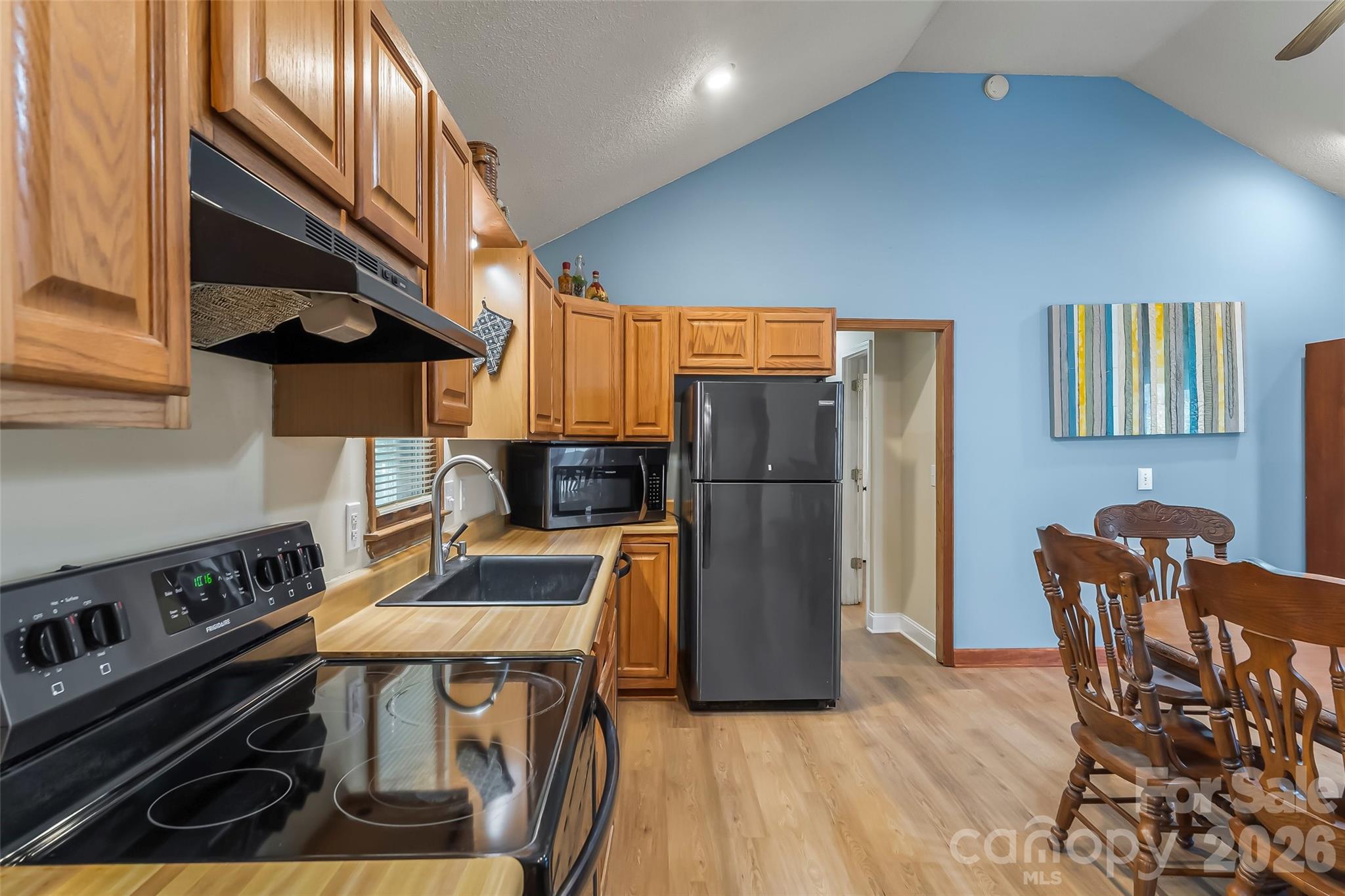 242 Plott Balsam Road Maggie Valley, NC 28751 - Photo 10 of 32 a kitchen with stainless steel appliances granite countertop a stove a refrigerator a dining table and chairs with wooden floor
