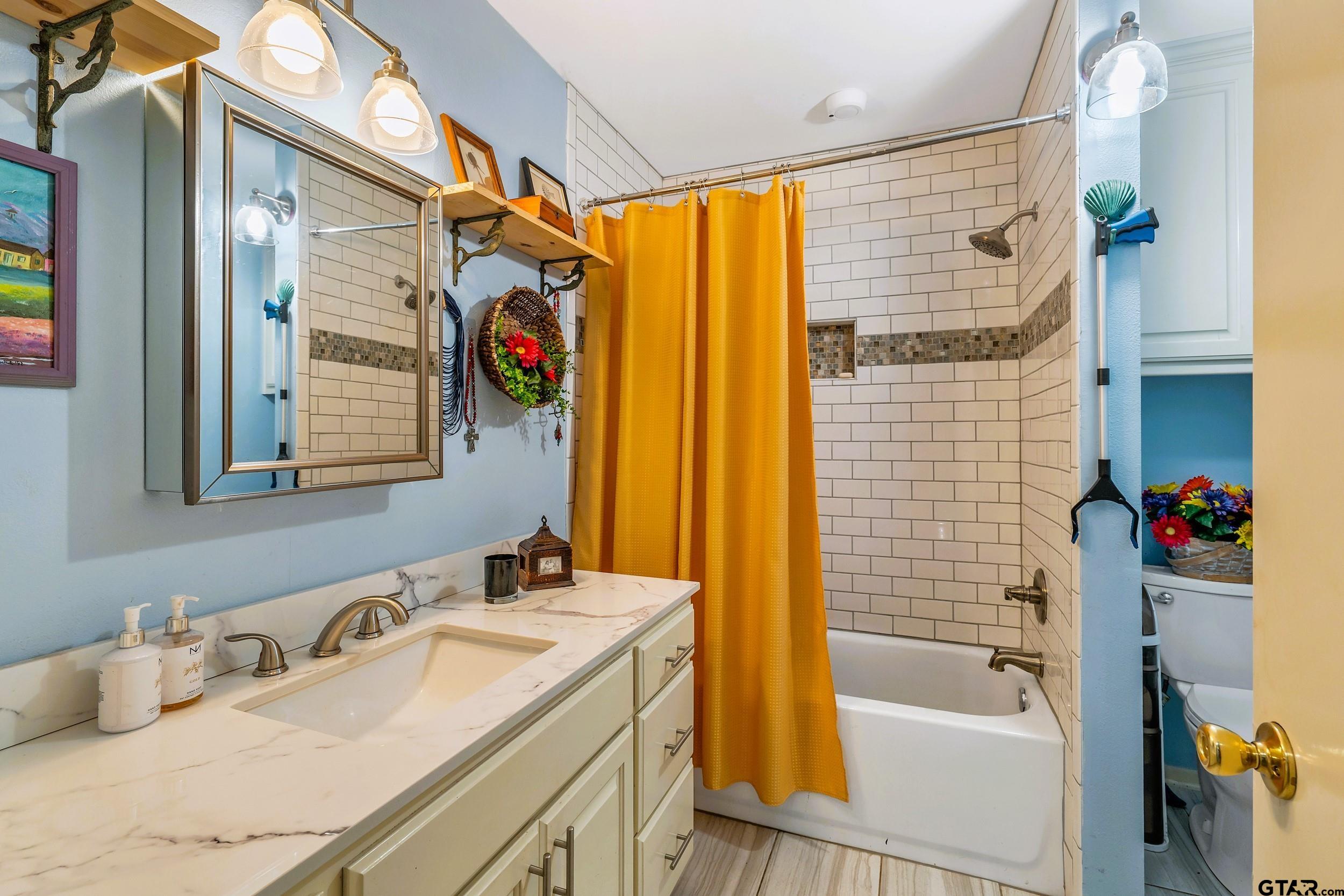 22982 Edgewater Drive Frankston, TX 75763 - Photo 22 of 26 a bathroom with a granite countertop sink a mirror a bathtub and shower
