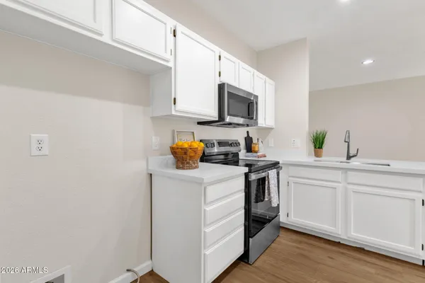 a kitchen with a sink a stove and white cabinets