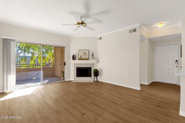 a view of empty room with wooden floor and fan