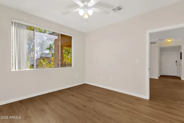 a view of an empty room with wooden floor and a window