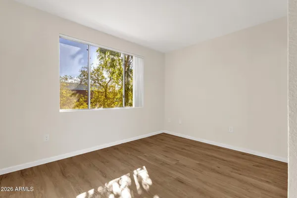 a view of an empty room with wooden floor and a window
