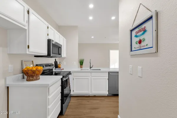 a kitchen with stainless steel appliances a stove top oven a sink a microwave a refrigerator and cabinets