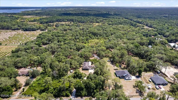 an aerial view of a houses with a yard and mountain
