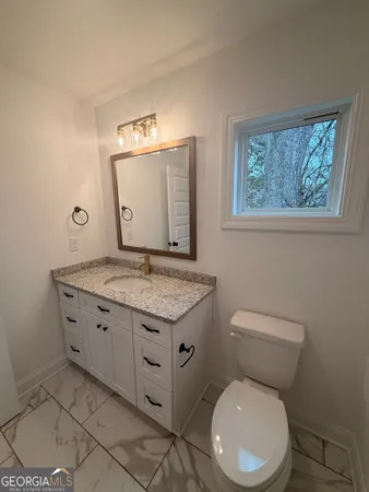 a bathroom with a granite countertop toilet and a sink