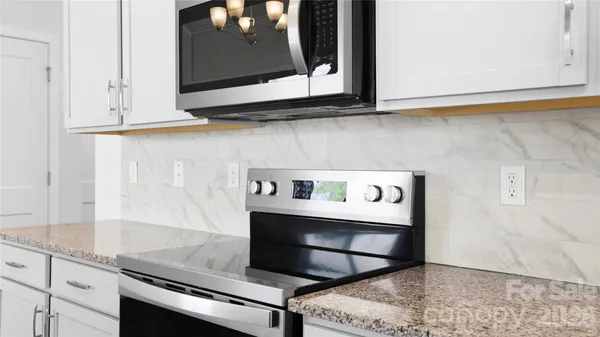 a kitchen with granite countertop white cabinets and appliances