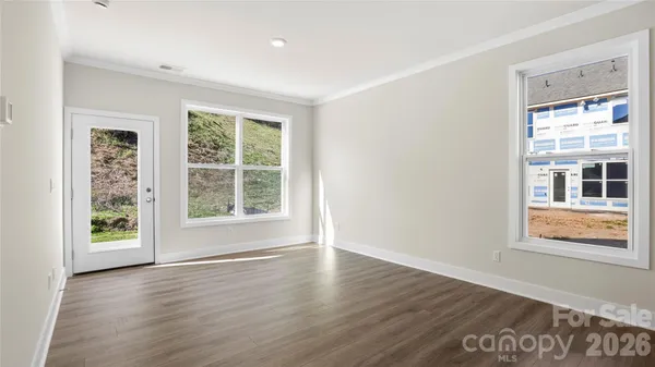 a view of an empty room with wooden floor and a window
