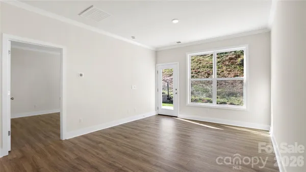 an empty room with wooden floor and windows