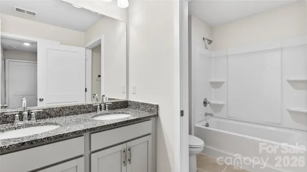a bathroom with a granite countertop tub sink and mirror