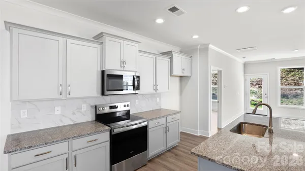 a kitchen with granite countertop white cabinets and stainless steel appliances