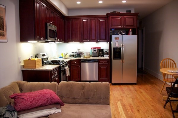 1089 Beacon Street, Unit 1 Brookline, MA 02446 - Photo 2 of 14 a kitchen with stainless steel appliances granite countertop a refrigerator a sink dishwasher with a dining table and chair