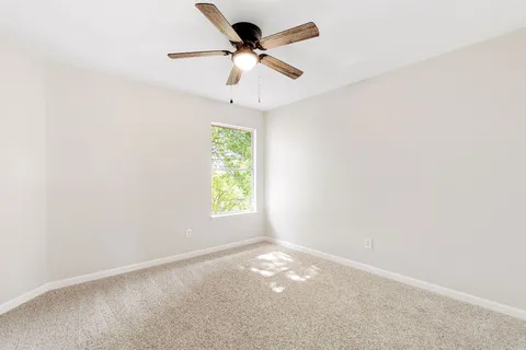 an empty room with a window and a fan