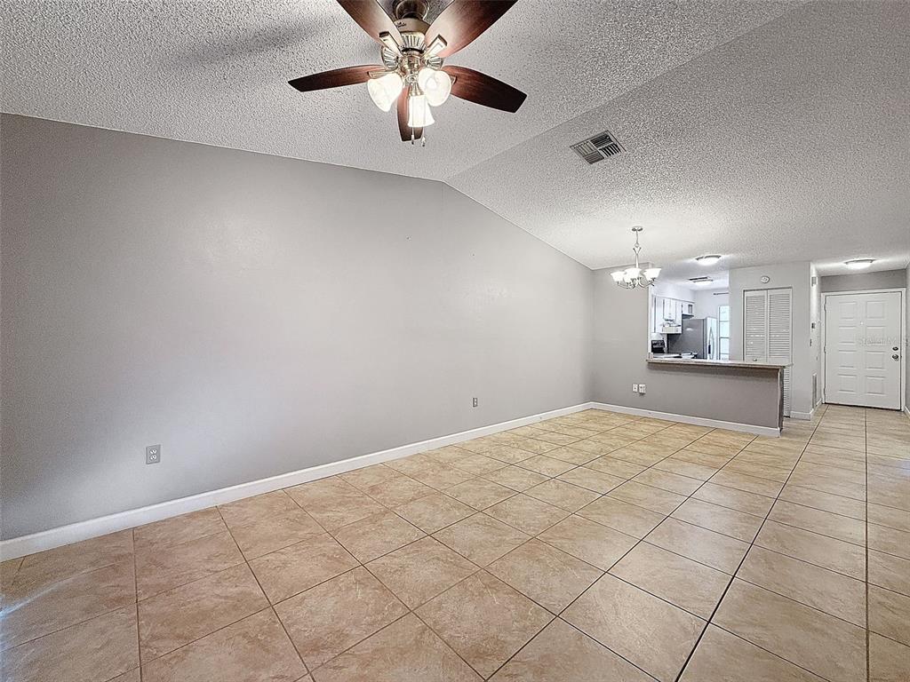 7116 Barclay Avenue, Unit B Spring Hill, FL 34609 - Photo 13 of 31 an empty room with kitchen and chandelier fan
