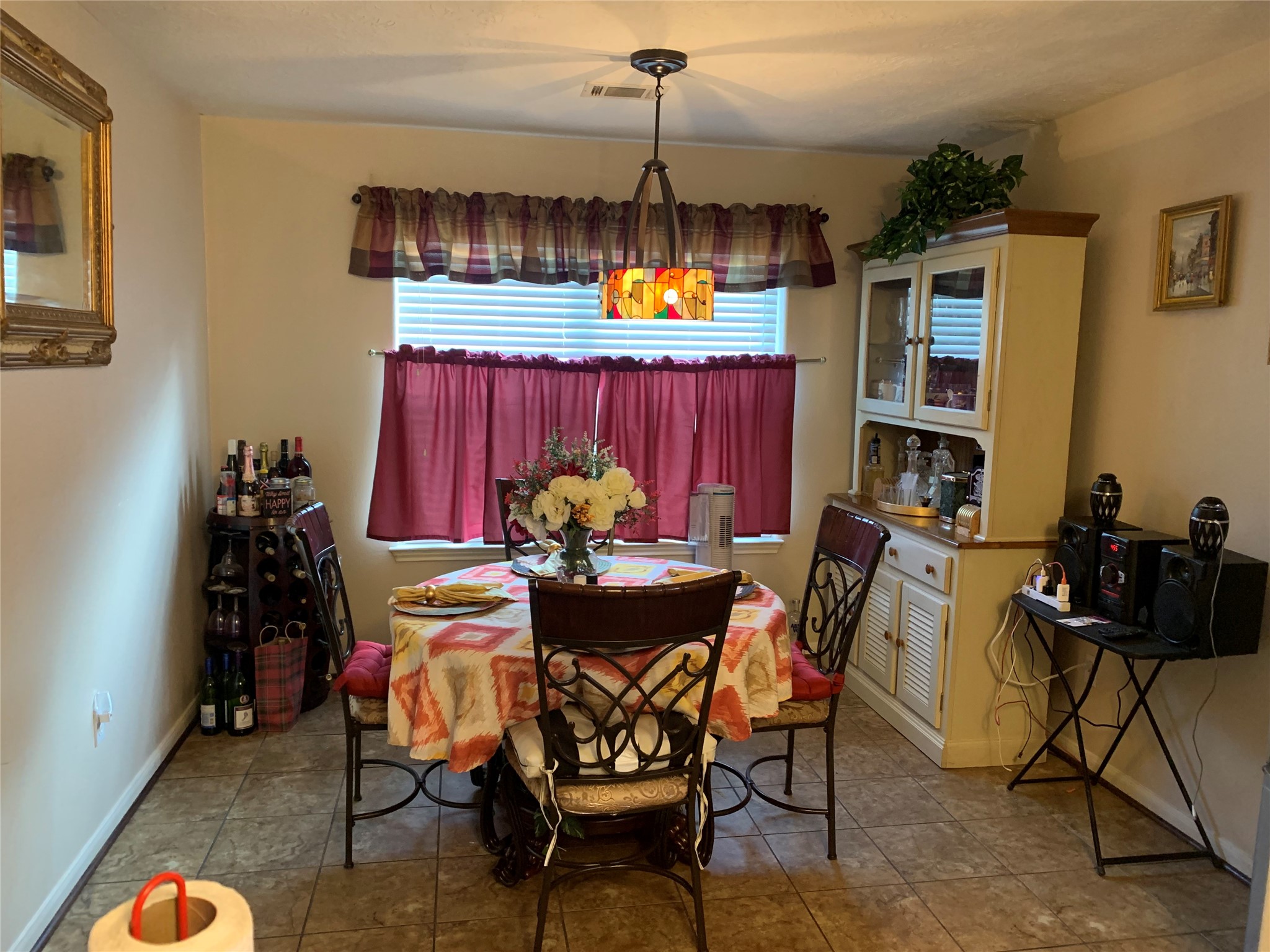 4630 Comal River Loop Spring, TX 77386 - Photo 4 of 12 Cozy dining area featuring a round table with ornate chairs, a decorative pendant light, and a hutch for storage. The space includes a wine rack and is accented with warm, red curtains. Ideal for intimate meals.