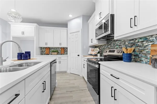 a kitchen with stainless steel appliances granite countertop a sink and dishwasher a stove top oven with white cabinets