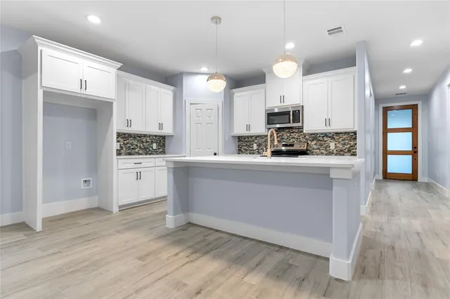 a kitchen with stainless steel appliances kitchen island wooden cabinets and fireplace