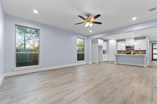 a view of an empty room with a window and wooden floor