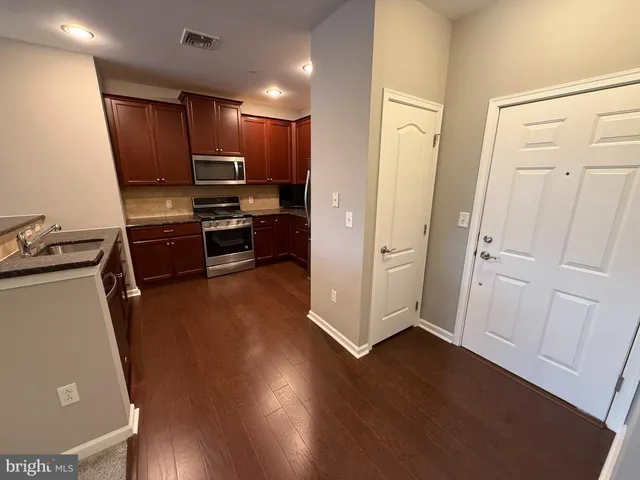 a kitchen with kitchen island granite countertop a stove top oven a sink and a refrigerator
