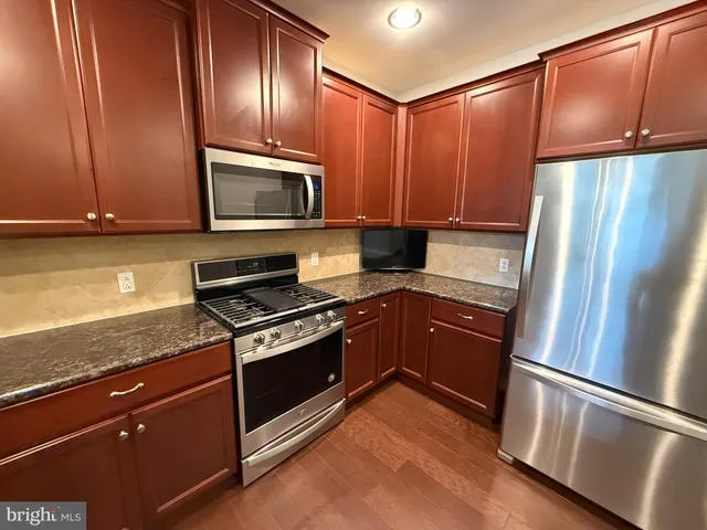 a kitchen with granite countertop wooden cabinets and a stove top oven