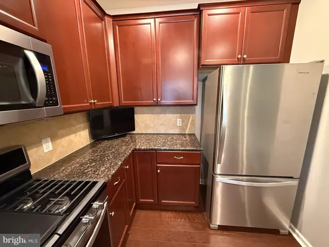 a kitchen with stainless steel appliances granite countertop a stove a sink and a microwave