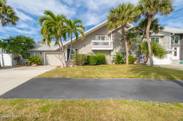a view of a house with a yard and palm trees