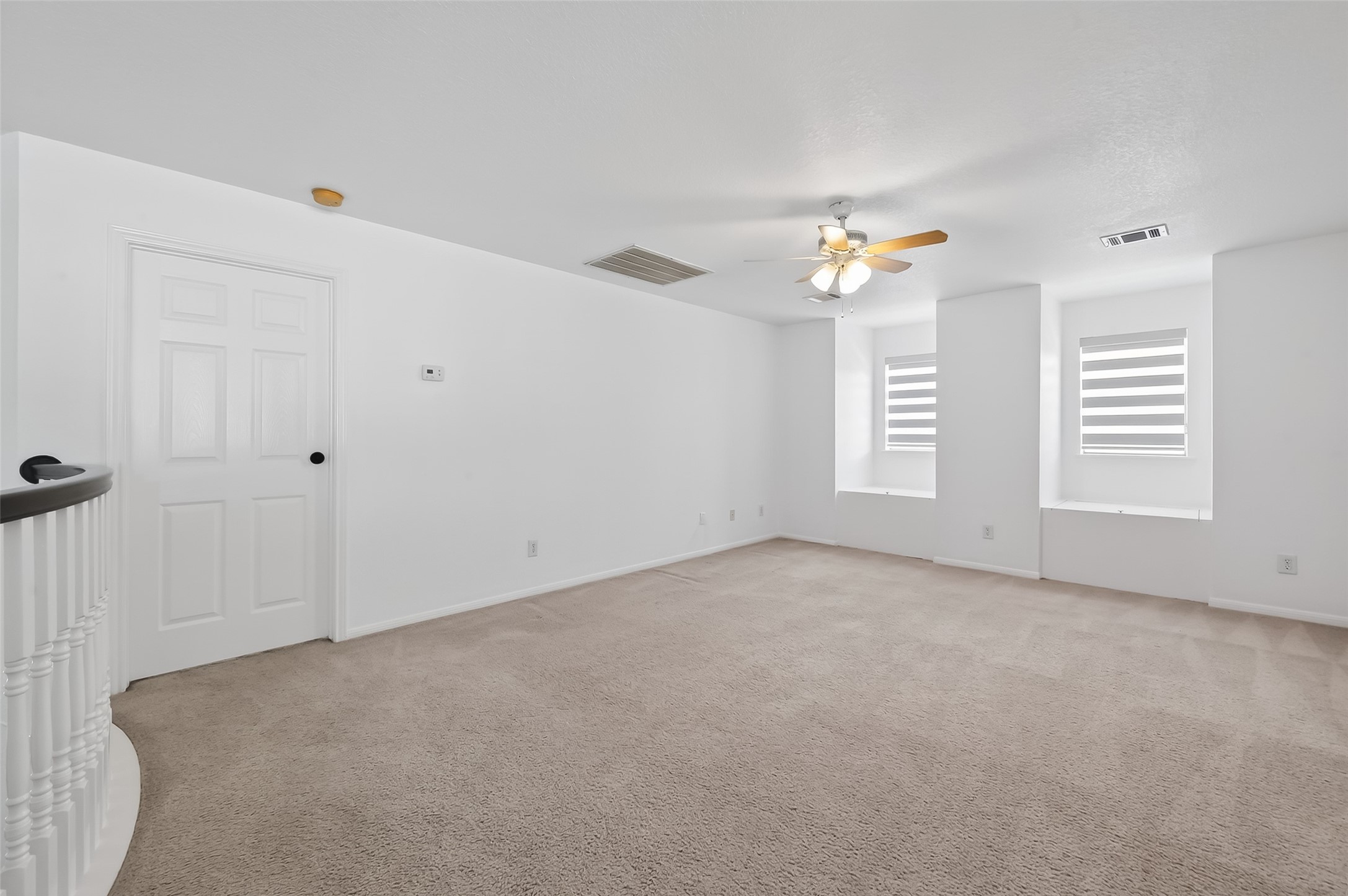 1311 Rene Court Sugar Land, TX 77479 - Photo 29 of 45 This room is spacious and bright with neutral carpet and white walls, featuring two windows with striped blinds, a ceiling fan, and a door. Ideal for a versatile living or office space.