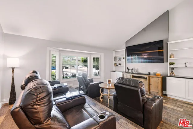 a living room with furniture a flat screen tv and a floor to ceiling window
