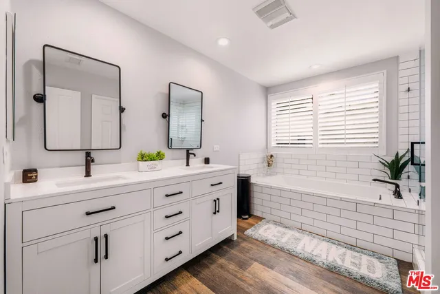 a bathroom with a double vanity sink mirror and next to a window