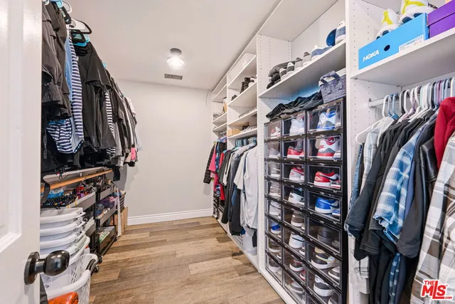a view of walk in closet with clothes and shoes