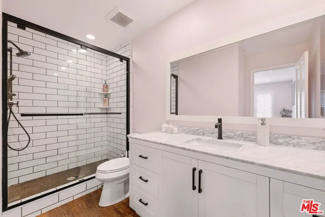 a bathroom with a granite countertop sink mirror vanity and toilet