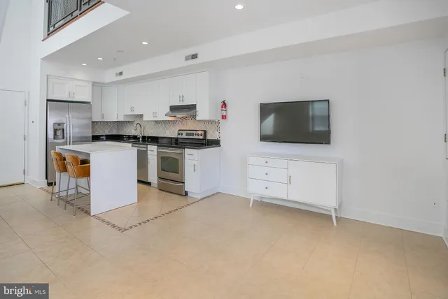 a kitchen with stainless steel appliances a stove top oven a sink a counter top space and cabinets