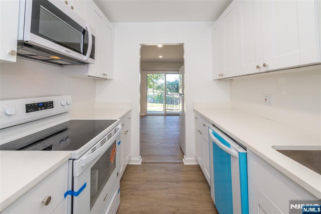 1111 River Road, Unit G5 Edgewater, NJ 07020 - Photo 6 of 20 a kitchen with stainless steel appliances granite countertop a white stove top oven and wooden floor