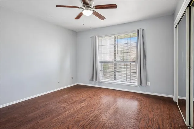 an empty room with wooden floor fan and windows