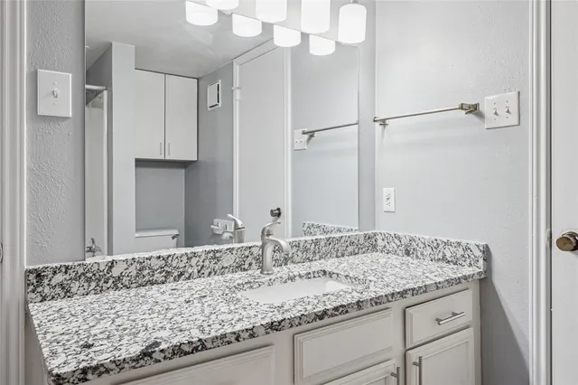 a bathroom with a granite countertop sink and a mirror