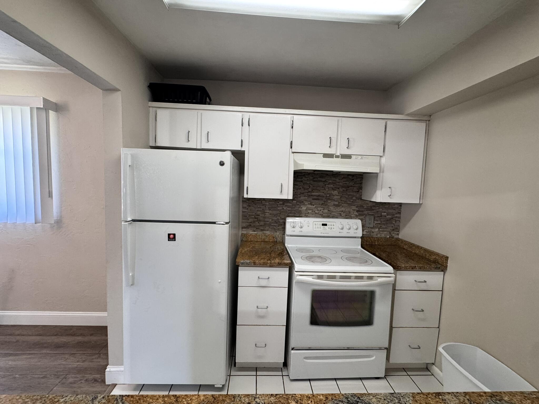 3124 Highway 441, Unit J1 Okeechobee, FL 34974 - Photo 7 of 40 a kitchen with white cabinets and white appliances