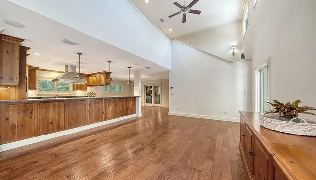 a kitchen with stainless steel appliances kitchen island granite countertop a refrigerator oven a sink with wooden cabinets and wooden floor