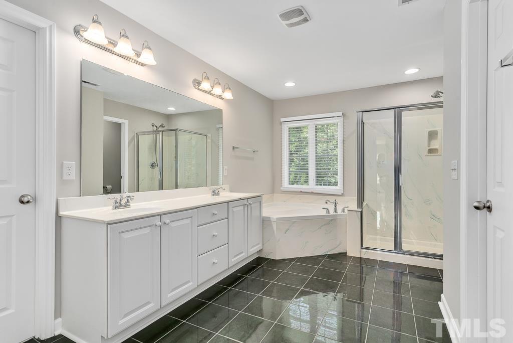 618 Red Cedar Circle Durham, NC 27712 - Photo 27 of 45 a bathroom with a double vanity sink a large mirror and a bathtub