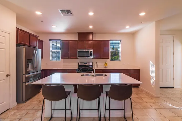 a kitchen with stainless steel appliances granite countertop a sink refrigerator and chairs